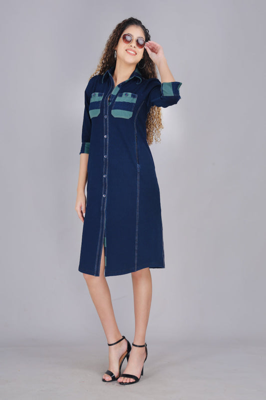 A woman wearing a long denim dress with green and blue striped pockets, button-up front, and two pockets. 